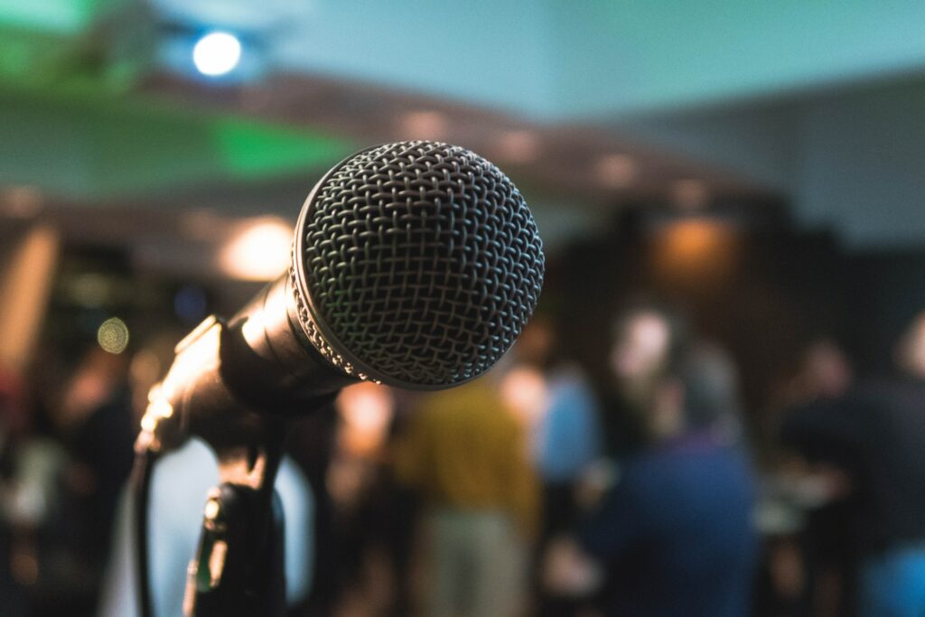 A picture of a microphone with a sitting audience in the background