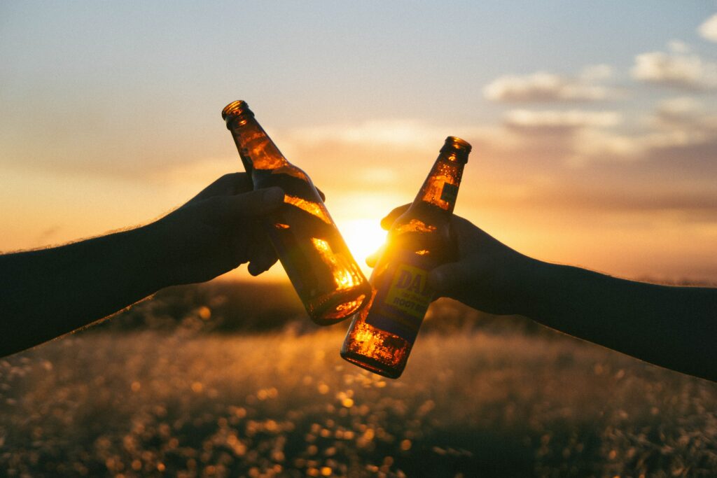 An Unsplash picture by Wil Stewart of two people giving a toast with a bottle of beer.